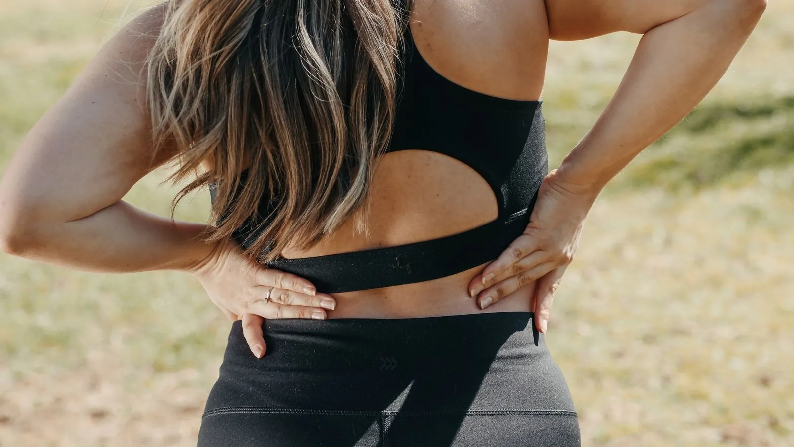 Persona con las manos en la zona baja de la espalda por dolor lumbar (lumbago)