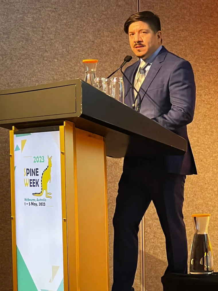 El Dr. Adrián Zárate exponiendo su trabajo sobre seguridad de tornillos pediculares en el podio de Spineweek 2023, Melbourne, Australia.